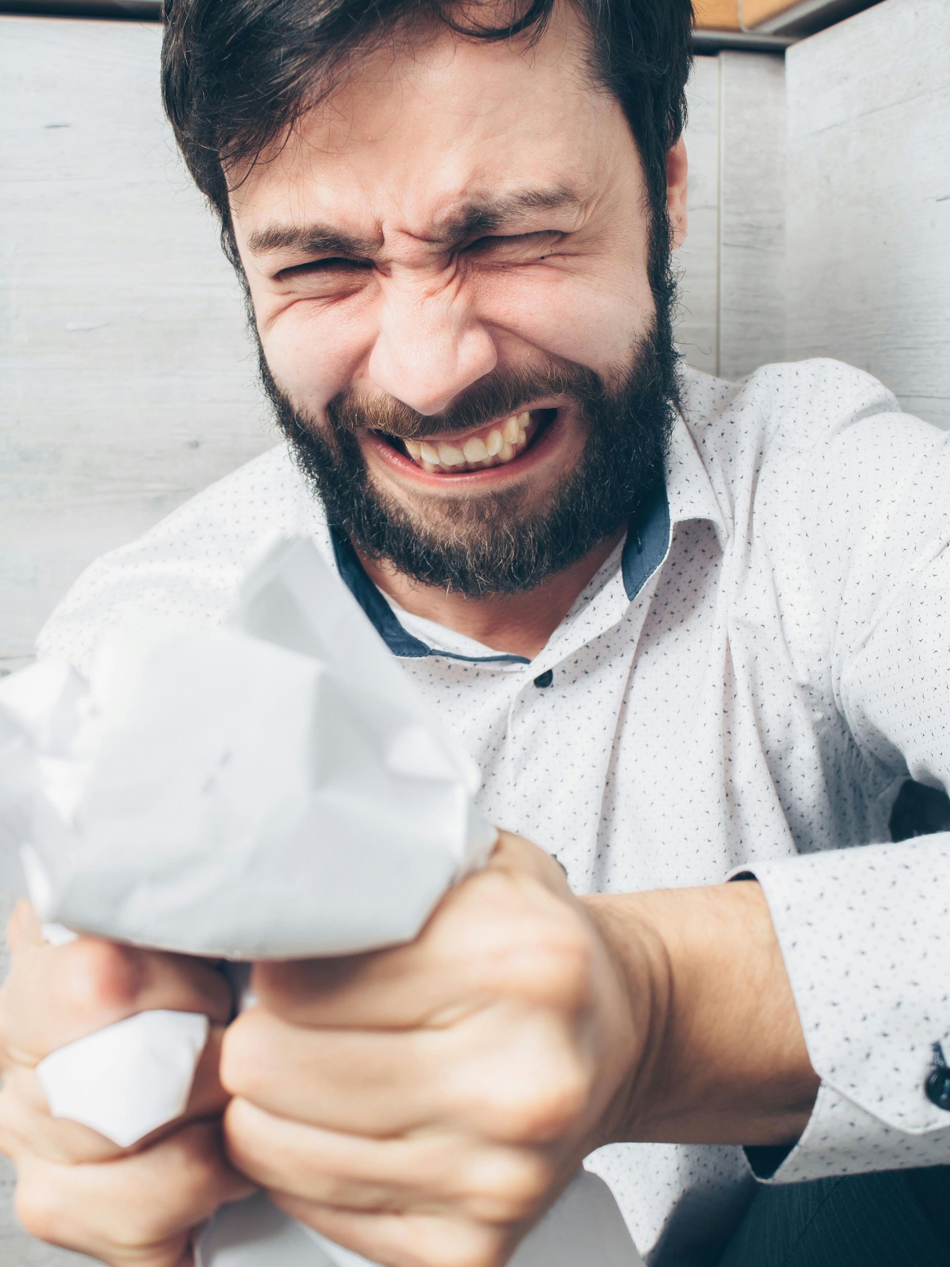A bearded man grimaces in visible frustration and anger