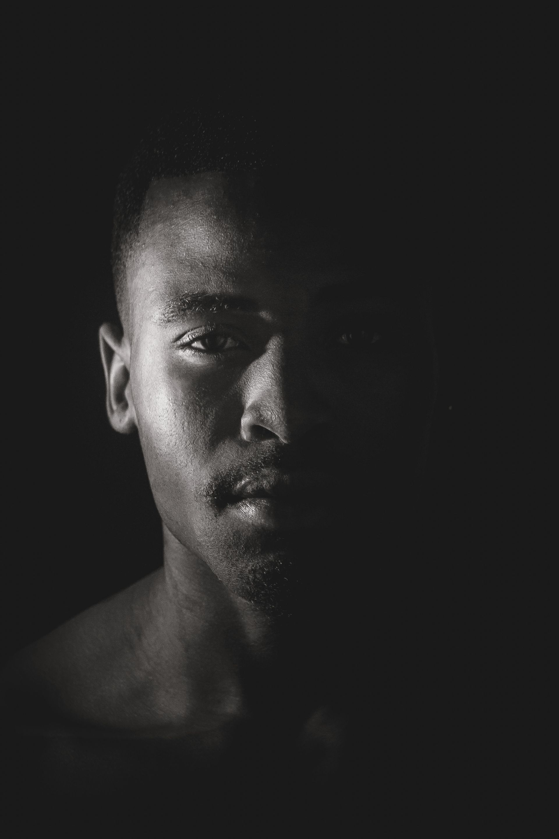 Dark, dramatic black-and-white close-up of a man's face
